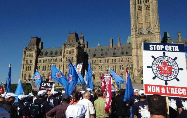 Marchers gather outside Parliament to protest the Canadian-EU Comprehensive Economic Tarde Agreement.