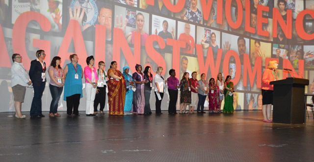 Female delegates to the ITF Congress take the stage in support of the organization’s “white ribbon: campaign after workplace violence to women.